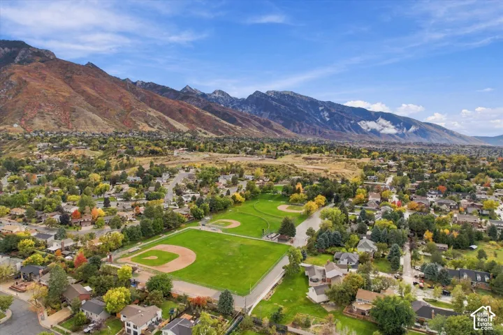 Aerial perspective of the property featuring a prominent mountain backdrop, direct proximity to a public recreation area with multiple ball fields, and established mature deciduous trees