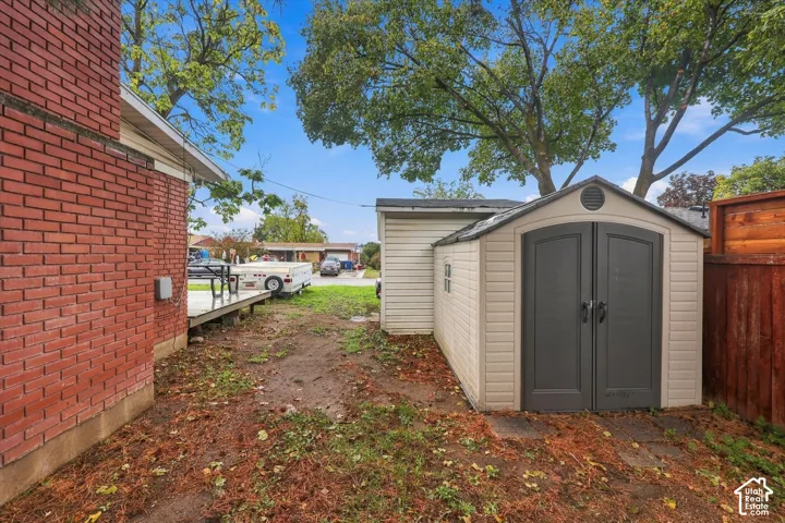 Red brick exterior siding, detached storage shed with double doors, and wood-panel perimeter fencing