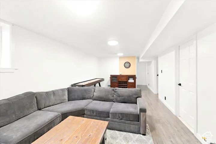 Neutral-toned interior space featuring wood-finish flooring, crisp white walls, flush-mount lighting, and a six-panel interior door