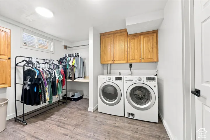 Laundry space featuring wood-finish flooring, built-in upper wooden cabinetry, and a horizontal window