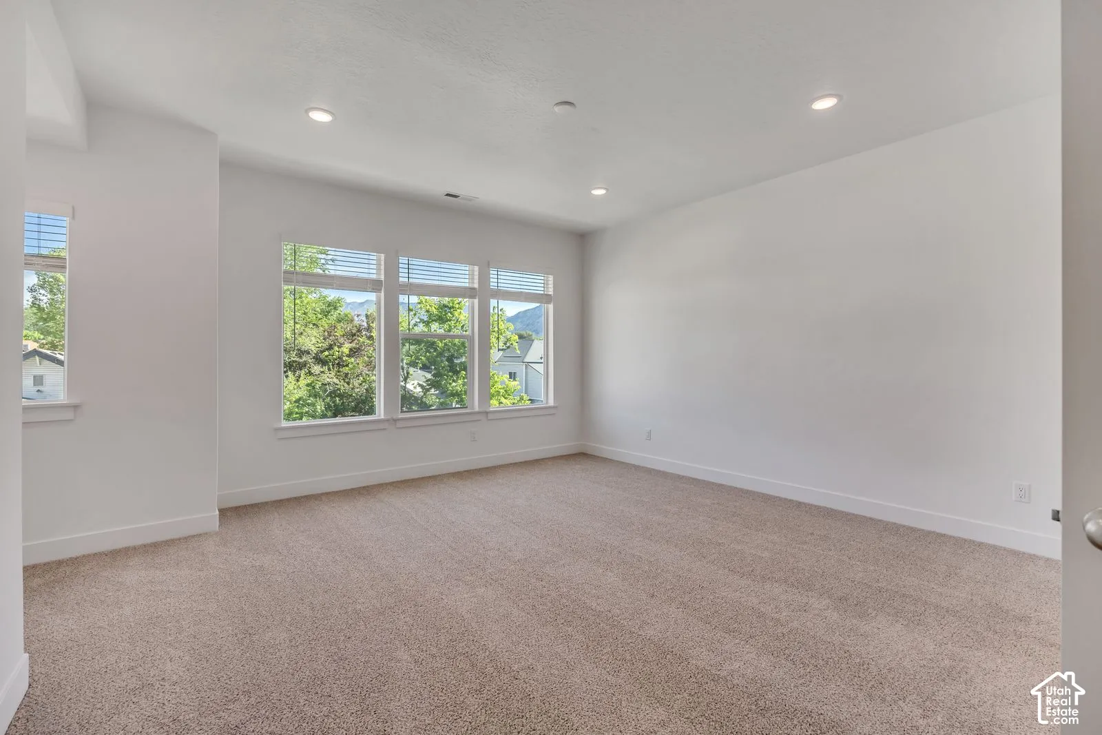 Neutral-toned carpeting, recessed ceiling lighting, and multiple windows featuring exterior mountain scenery