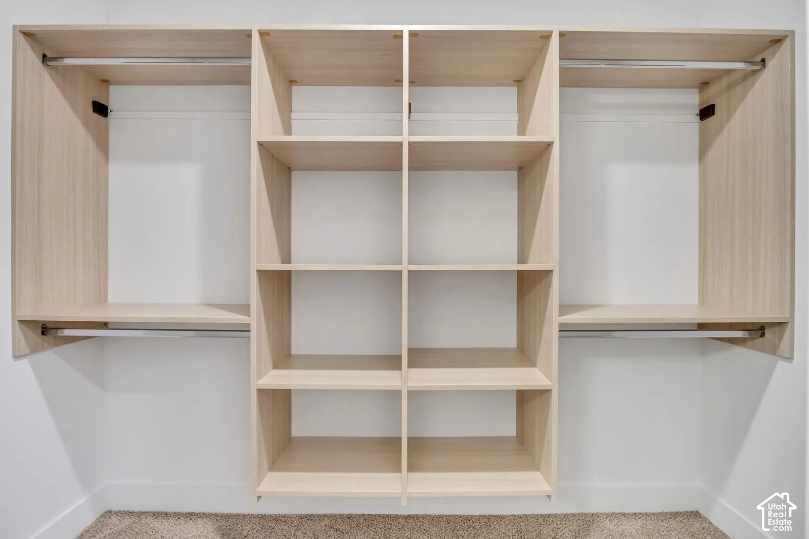 Custom built-in closet organization system featuring light wood-finish shelving, multiple open storage compartments, and integrated metal hanging rods