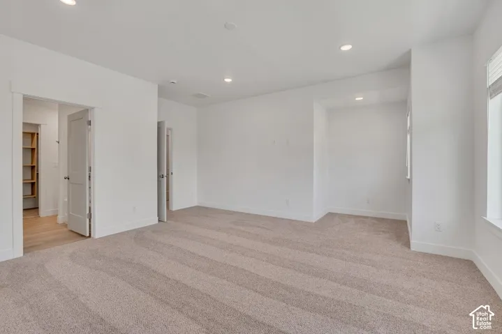 Neutral-toned wall-to-wall carpeting, recessed ceiling lighting, and solid-core interior doors with framed casing