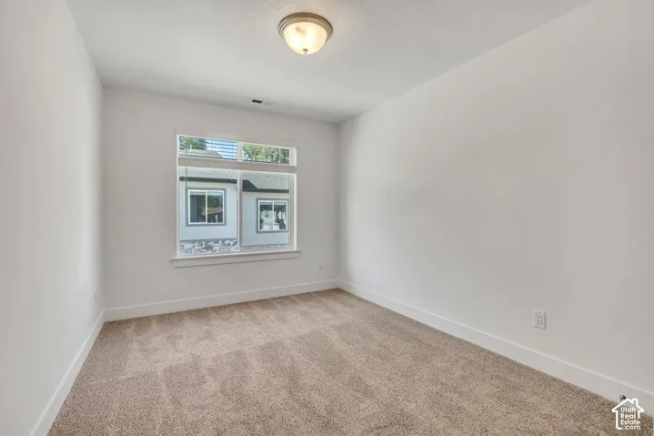 Interior space featuring neutral-toned carpeting, crisp white walls, a multi-pane window with a sill, and a semi-flush mount ceiling fixture