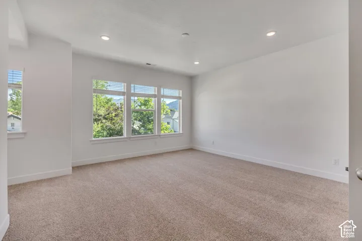 Neutral-toned carpeting, recessed ceiling lighting, and multiple windows featuring exterior mountain scenery
