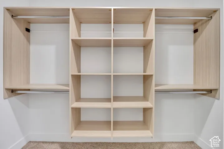 Custom built-in closet organization system featuring light wood-finish shelving, multiple open storage compartments, and integrated metal hanging rods