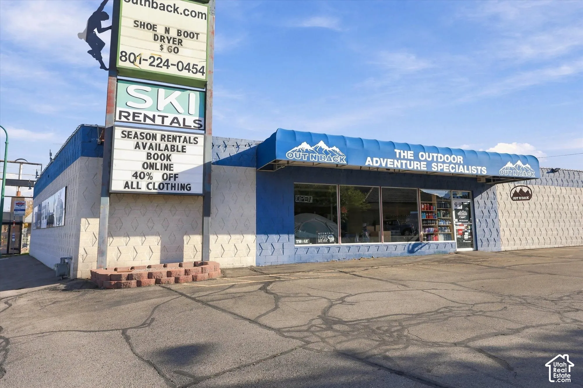 Commercial storefront featuring expansive glass display windows, blue fabric awning, patterned masonry exterior, and an integrated pole-mounted signage structure
