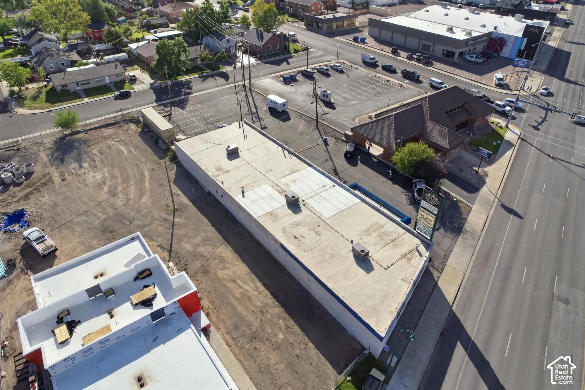 Commercial property featuring a flat roofline, integrated rooftop HVAC units, an on-site parking area, and street-level access