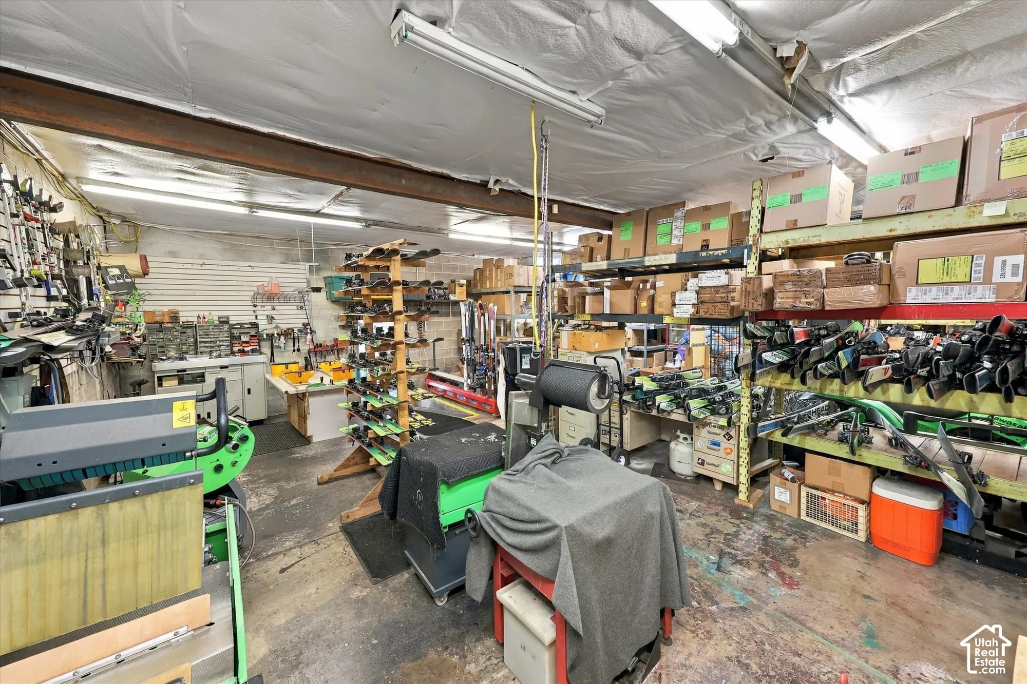 Workshop area featuring concrete flooring, exposed steel structural beams, and overhead fluorescent lighting