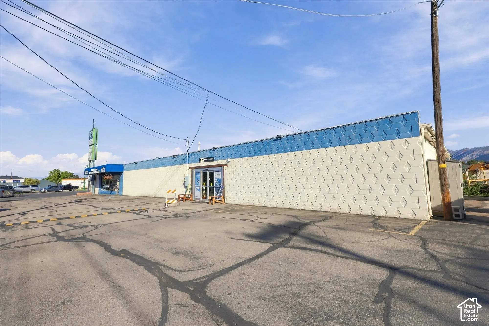 Commercial property featuring a paved asphalt parking lot, textured masonry exterior walls, blue decorative paneling, and an automated glass entry door