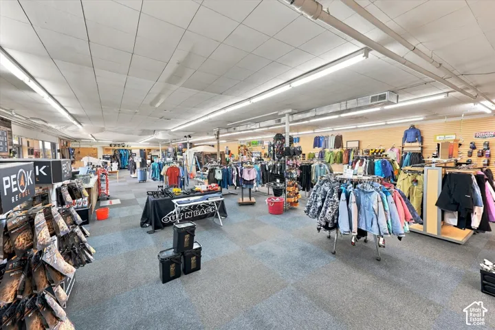 Open-concept commercial interior featuring expansive floor area, drop ceiling with integrated linear fluorescent lighting, and slatwall paneling