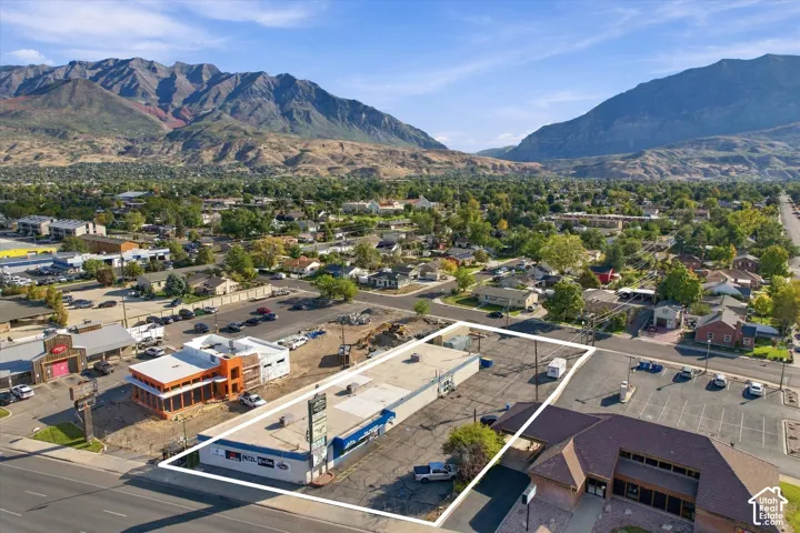Commercial property featuring a flat-roof structure, asphalt parking lot, and prominent signage, situated against a mountain backdrop