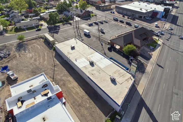 Commercial property featuring a flat roofline, integrated rooftop HVAC units, an on-site parking area, and street-level access