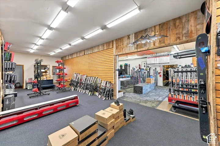 Commercial space featuring horizontal slat-wall shelving, rustic wood-panel accenting, linear fluorescent lighting, and commercial-grade carpeting