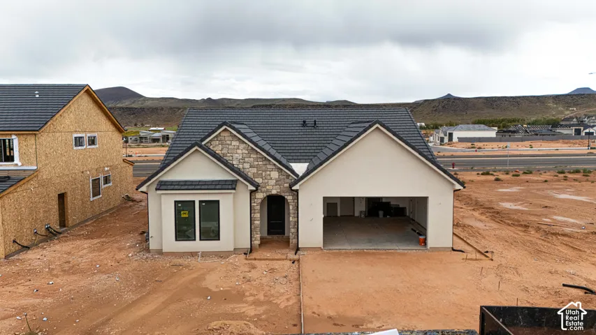Single-level residence featuring a stucco and stone exterior, tile roofing, and an attached two-car garage