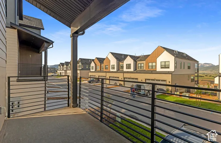 Covered balcony featuring concrete flooring, black metal railing, and support pillars