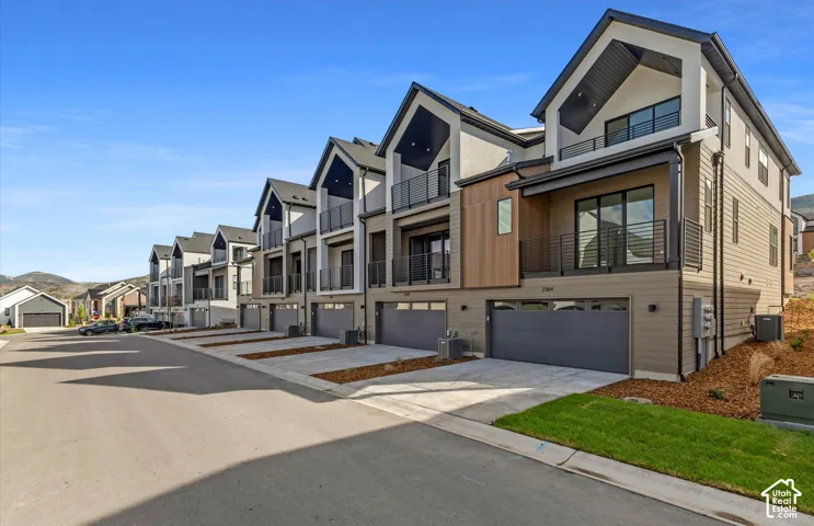 Contemporary multi-level exterior featuring horizontal lap siding, vertical wood-finish panels, multiple private balconies with metal railings, and attached two-car garages