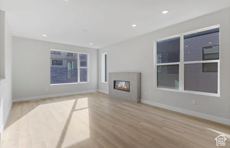 Living area featuring wood-finish flooring, recessed lighting, expansive windows, and a tile-surround fireplace