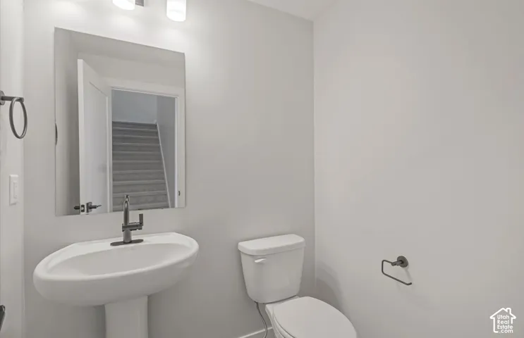 Pedestal sink with a modern metal faucet, wall-mounted mirror, two-light fixture, and matte black hardware