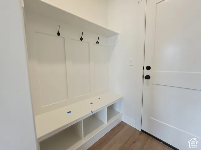 Built-in mudroom cabinetry featuring millwork detailing, overhead shelving, matte black hardware, and integrated lower storage cubbies set against wood-finish flooring