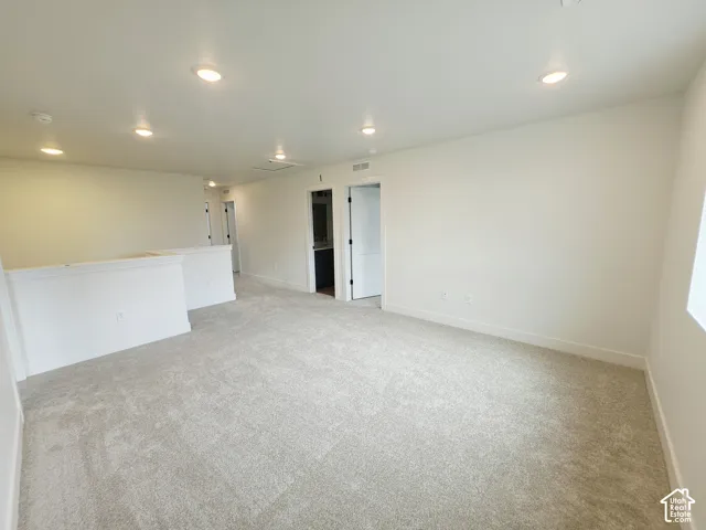 Spacious interior featuring neutral wall-to-wall carpeting, recessed ceiling lighting, and a partial-height partition wall