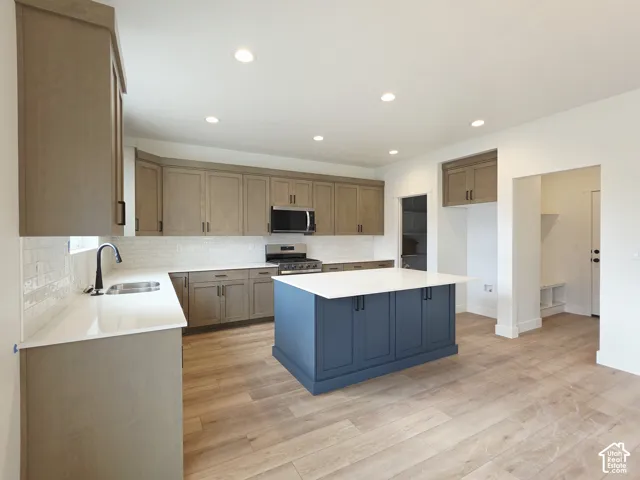Kitchen featuring wood-finish cabinetry, a contrasting central island with white countertop, subway tile backsplash, recessed lighting, and wood-finish flooring