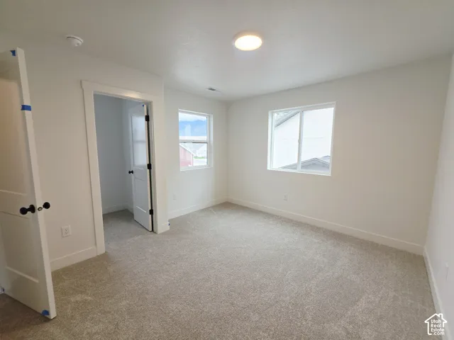 Neutral-toned wall-to-wall carpeting, dual-pane windows, interior door with matte black hardware, and overhead flush-mount lighting