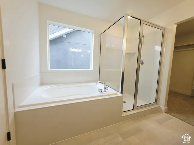 Bathroom featuring an oval soaking tub with deck-mounted faucet, separate shower with glass enclosure and chrome fixtures, and tile flooring