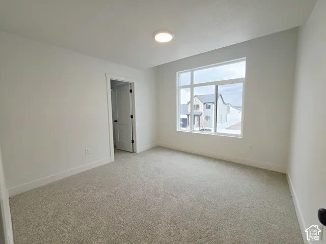 Neutral wall paint, plush carpeting, large picture window with transoms, and a solid-core paneled interior door with matte black hardware