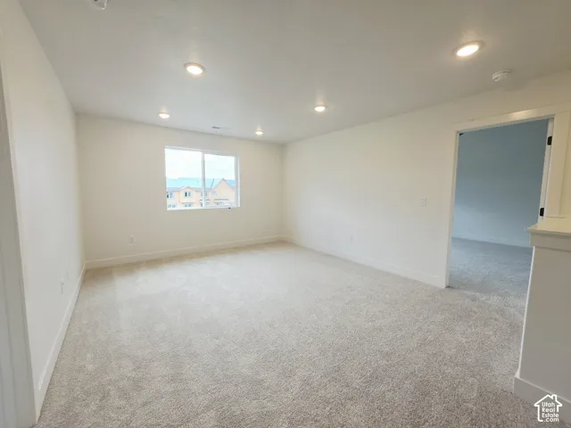 Neutral interior space featuring high-pile wall-to-wall carpeting, recessed LED lighting, and a single-hung window with white framing