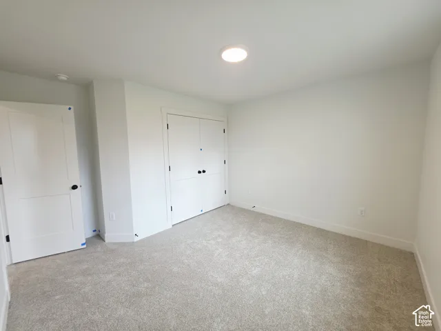 Neutral interior featuring neutral-toned carpeting, white walls, dual-panel closet doors, single-panel interior door, and flush-mount ceiling lighting