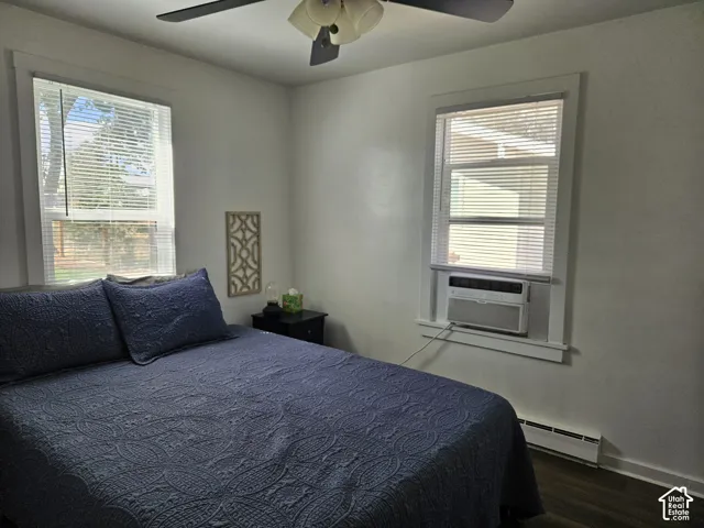 Room featuring wood-finish LVP flooring, two windows with horizontal blinds, and an integrated ceiling fan with light fixture and Window AC Unit.