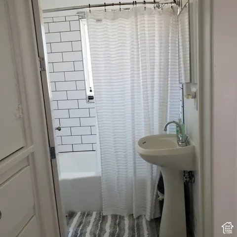 Bathroom featuring a white pedestal sink, chrome faucet, bathtub surround with white subway tile and dark grout.