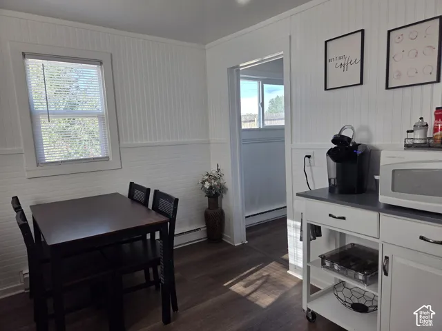 White beadboard wall paneling throughout kitchen, wood-finish LVP flooring, and natural light from windows with horizontal blinds (2nd Window AC unit s installed in this window above table now)
