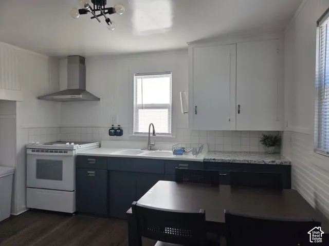 Kitchen featuring two-tone cabinetry, Laminate countertops, original washboard sink with Metal base, and a stainless-steel range hood over range. The kitchen also features beadboard wall paneling, and wood-finish LVP flooring