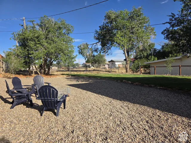 Private - expansive outdoor space featuring a graveled ground cover, manicured lawn area, mature trees, and perimeter fencing.