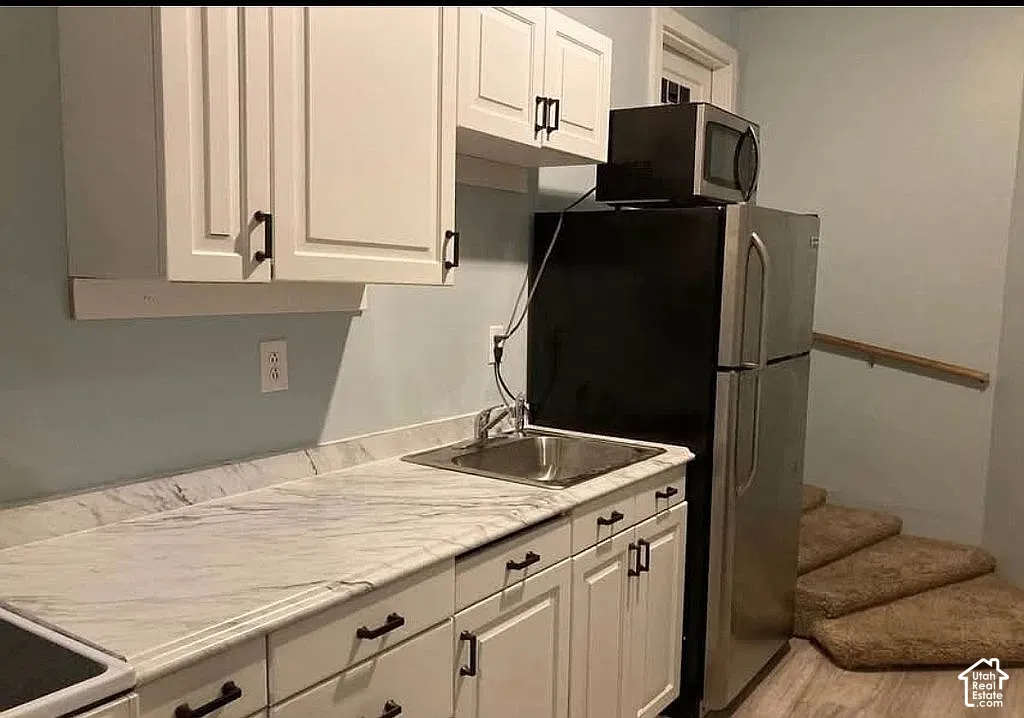Kitchenette area featuring white shaker-style cabinetry, stone-patterned countertops, a stainless steel drop-in sink, and matte black hardware