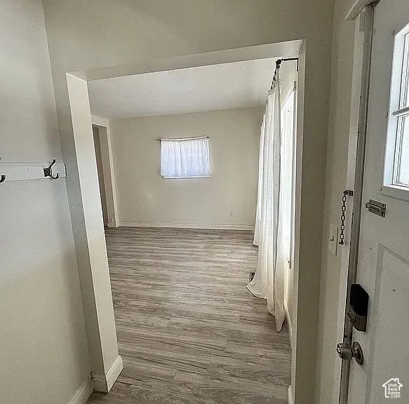 Interior entryway featuring wood-finish flooring, a wall-mounted hook rail, and a paneled entry door with a deadbolt lock