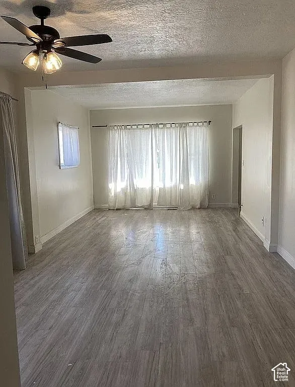 Interior space featuring wood-finish flooring, recessed wall alcoves, and a matte black ceiling fan with integrated lighting