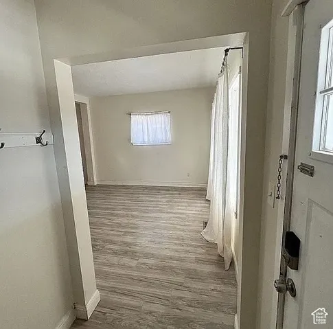 Interior entryway featuring wood-finish flooring, a wall-mounted hook rail, and a paneled entry door with a deadbolt lock
