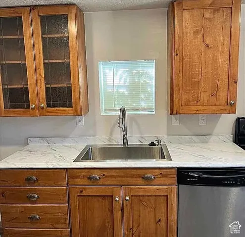 Natural wood-finish cabinetry featuring glass-paneled uppers, stone-patterned laminate countertop, stainless steel undermount sink, and high-arc pull-down faucet
