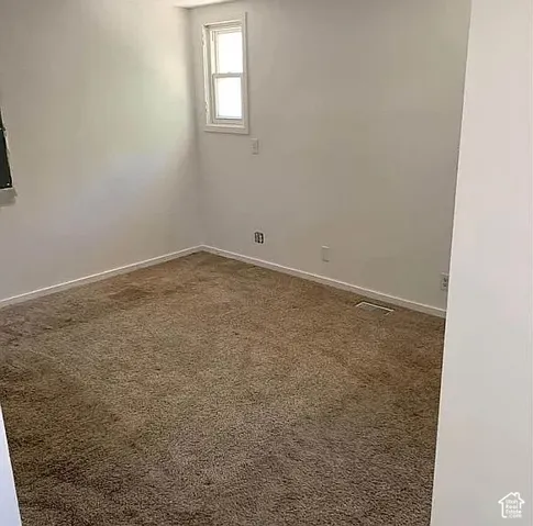 Neutral-toned interior space featuring wall-to-wall carpeting and a single-hung window with white casing