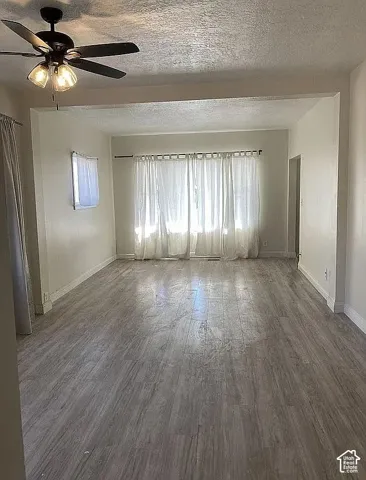Interior space featuring wood-finish flooring, recessed wall alcoves, and a matte black ceiling fan with integrated lighting