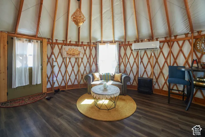 Circular interior structure featuring exposed lattice wood framing, wood-finish flooring, a wall-mounted ductless mini-split system, and a decorative pendant light fixture