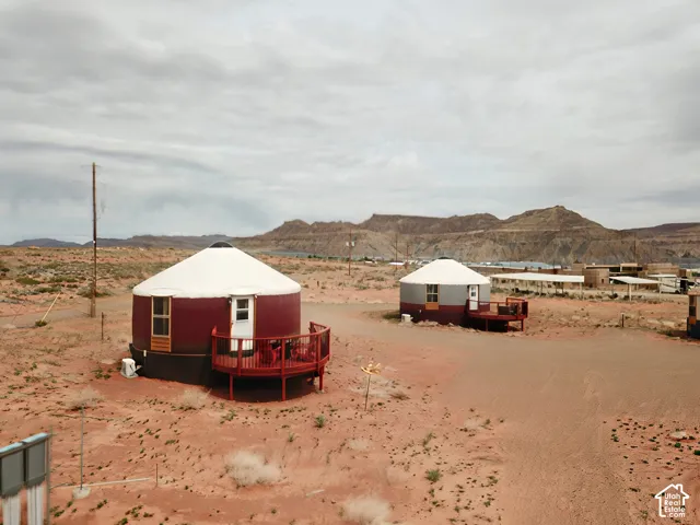 Circular structures featuring multi-tone exterior siding, white roof domes, and private elevated wooden decks set against a desert landscape with mountain backdrops