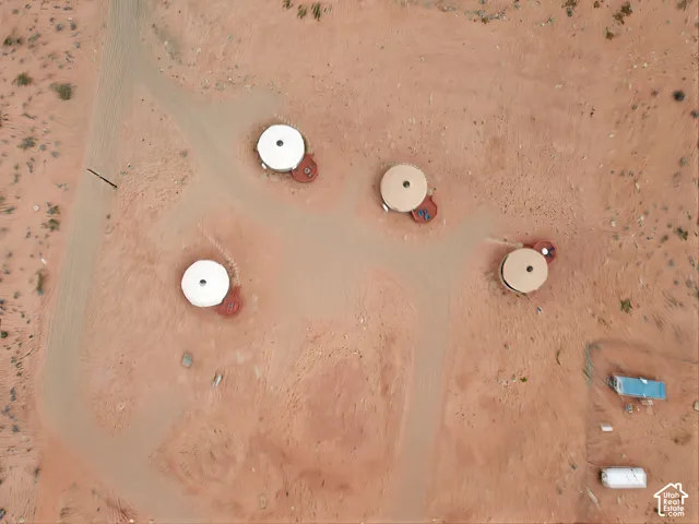 Aerial view of a desert property featuring four circular structures with attached decking, unpaved access paths, and arid topography
