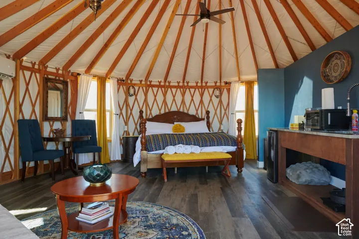Circular structure featuring exposed radial roof rafters, lattice-work walls, wood-finish flooring, a ceiling fan, and built-in kitchenette cabinetry