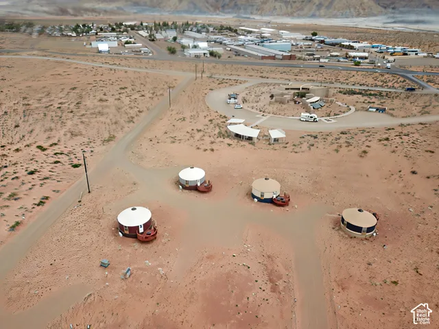 Aerial perspective of a high-desert property featuring four circular detached structures with attached wooden decks, surrounded by native desert terrain and mountain backdrops