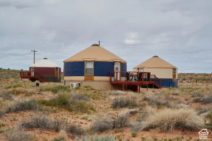 Three circular dwellings featuring domed roofs, elevated wood decks, and desert landscape integration