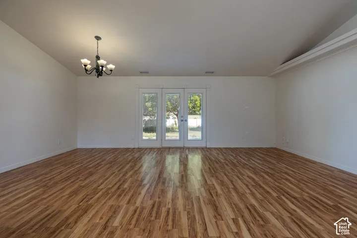 Vaulted ceilings, wood-finish flooring, multi-pane glass door, and a five-light chandelier